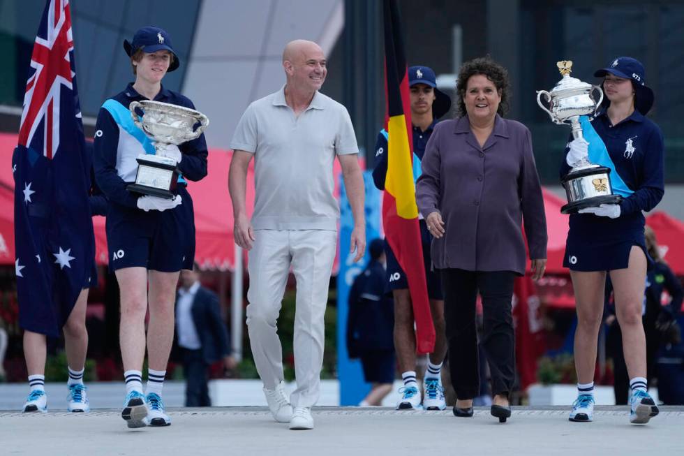 Former Grand Slam champions Andre Agassi and Evonne Goolagong Cawley walk with ball kids carryi ...