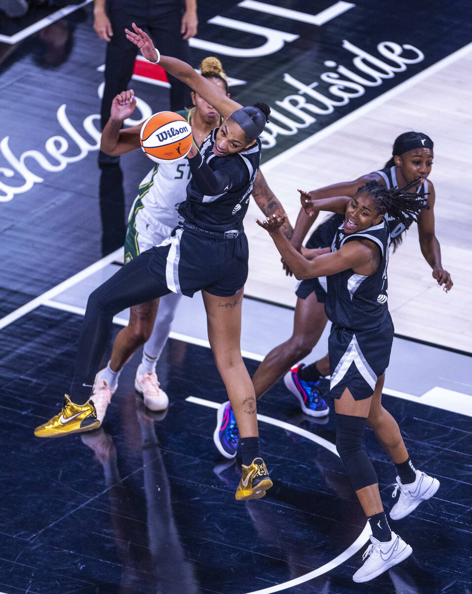 Aces center A'ja Wilson (22) taps back a rebound with help from guard Tiffany Hayes (15) agains ...