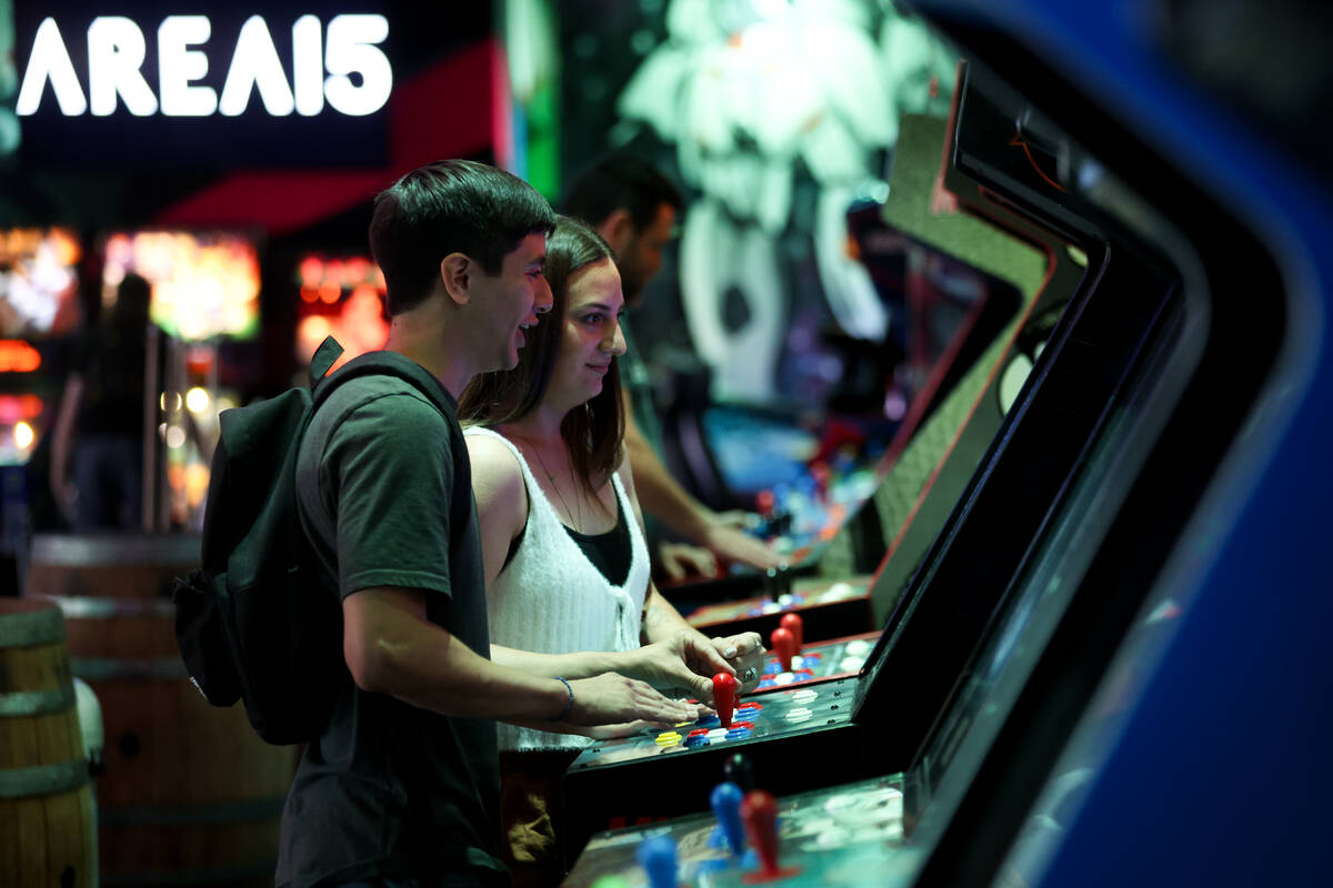 Josiah Montoya, left, and Isabella Hefty, of Pueblo, Colorado, play arcade games in Asylum Bar ...