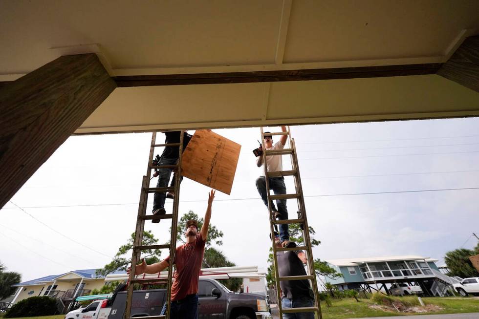 Jerry McCullen, top of ladder left, and Carson Baze, top of ladder right, put plywood over the ...