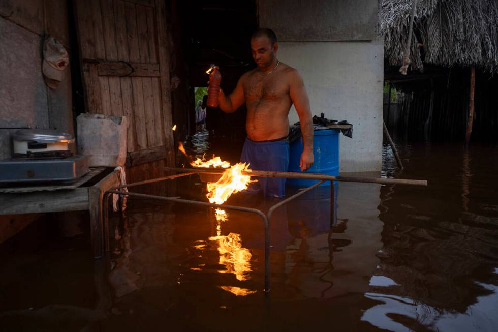 A man lights charcoal to cook dinner in his flooded home after the passage of Hurricane Helene ...