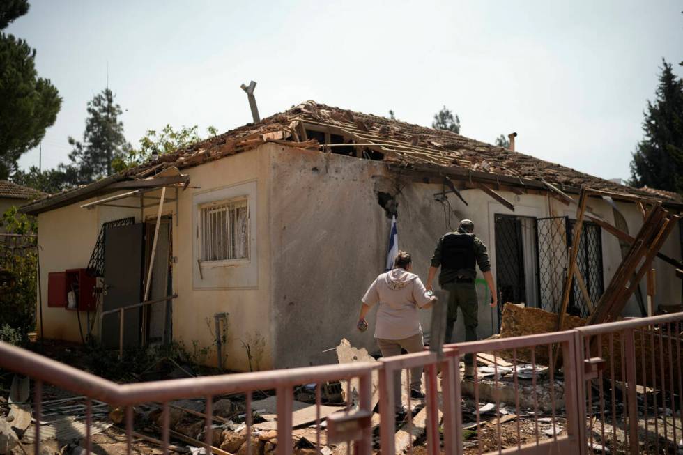 People look at a damaged house that was hit by a rocket fired from Lebanon, near Safed, norther ...