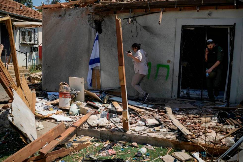 People look at a damaged house that was hit by a rocket fired from Lebanon, near Safed, norther ...