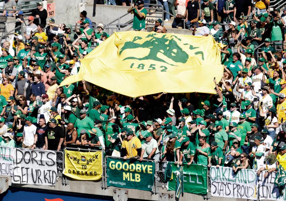 Oakland Athletics fans display signs and wave a flag as they watch the final home game against ...