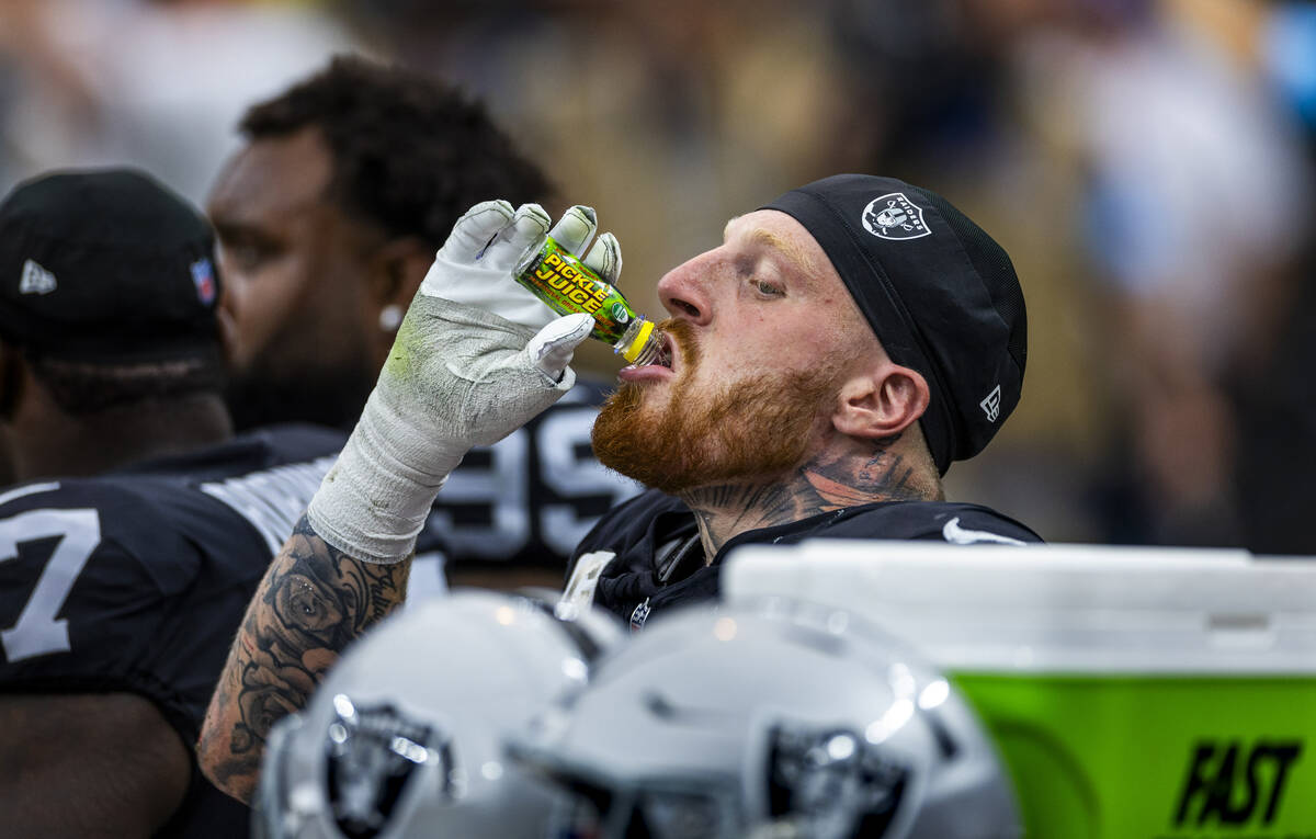 Raiders defensive end Maxx Crosby (98) drinks a bottle of Pickle Juice on the bench against the ...