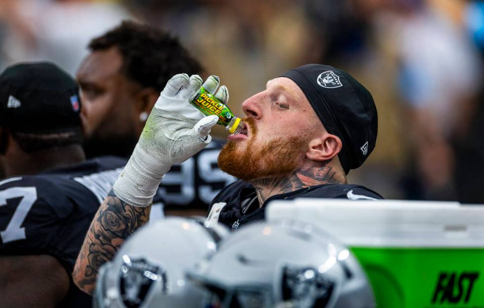 Raiders defensive end Maxx Crosby (98) drinks a bottle of Pickle Juice on the bench against the ...