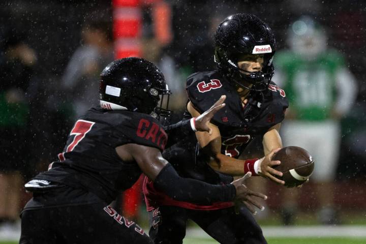 Las Vegas quarterback Tanner Vibabul (3) hands the ball off to running back Torrell Harley (7) ...