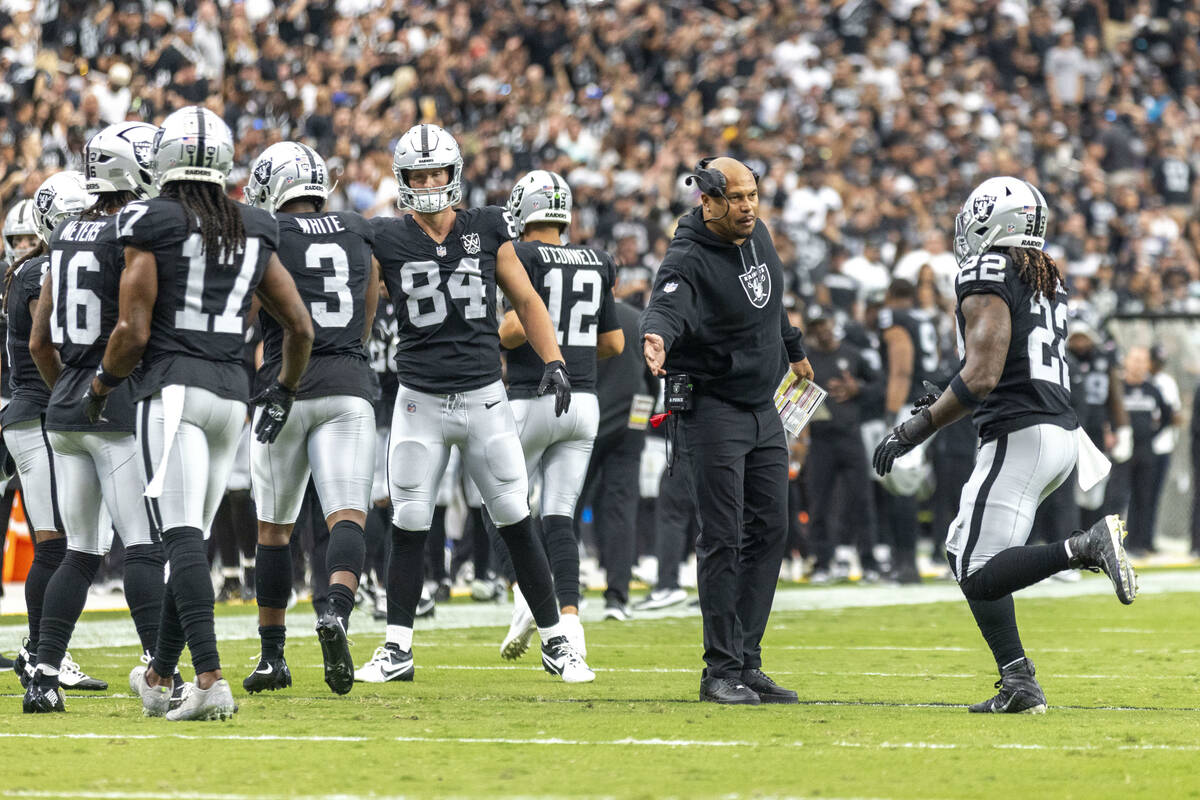 Raiders head coach Antonio Pierce greets Raiders running back Alexander Mattison (22) after his ...