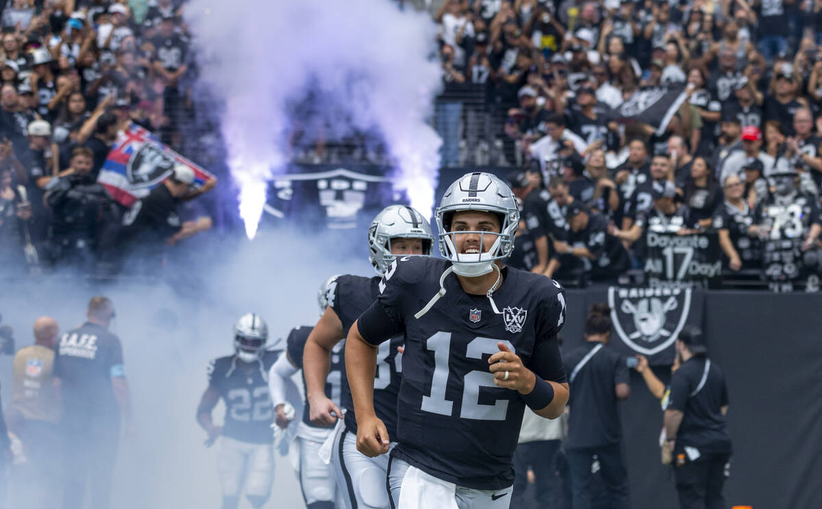 Raiders quarterback Aidan O'Connell (12) and teammates run onto the field from the tunnel befor ...