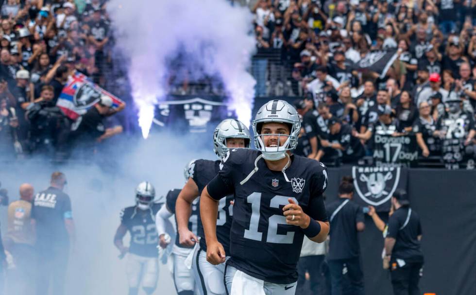 Raiders quarterback Aidan O'Connell (12) and teammates run onto the field from the tunnel befor ...