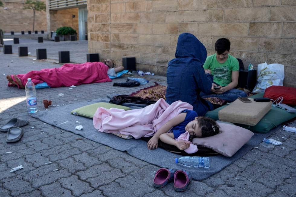 A family sleep on the ground in Beirut's corniche area after fleeing the Israeli airstrikes in ...