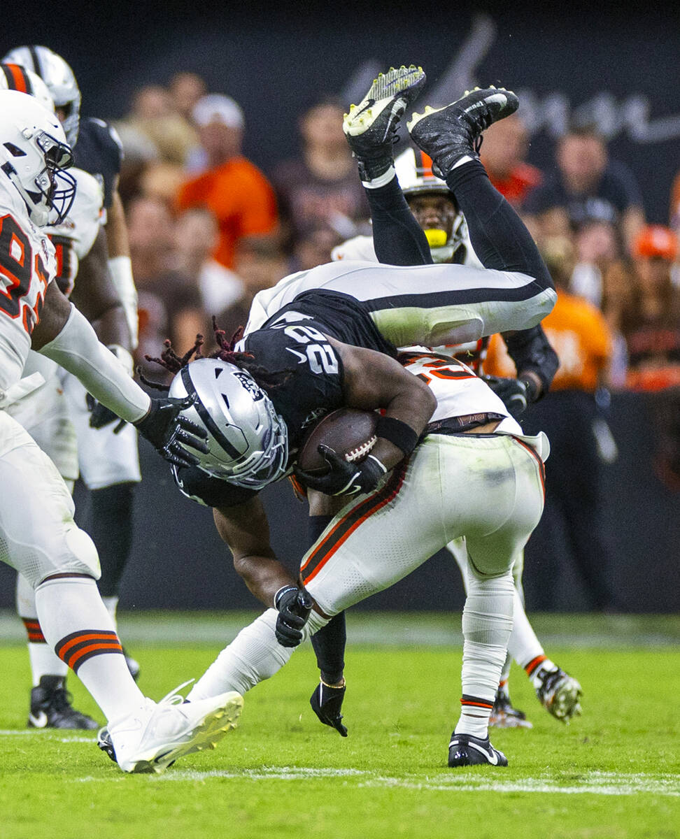 Raiders running back Alexander Mattison (22) is upended on a run by Cleveland Browns cornerback ...