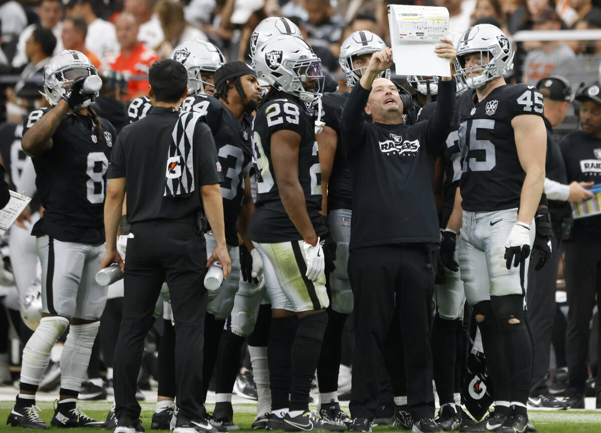 Raiders special teams coordinator Tom McMahon talks to review his book from the sidelines durin ...