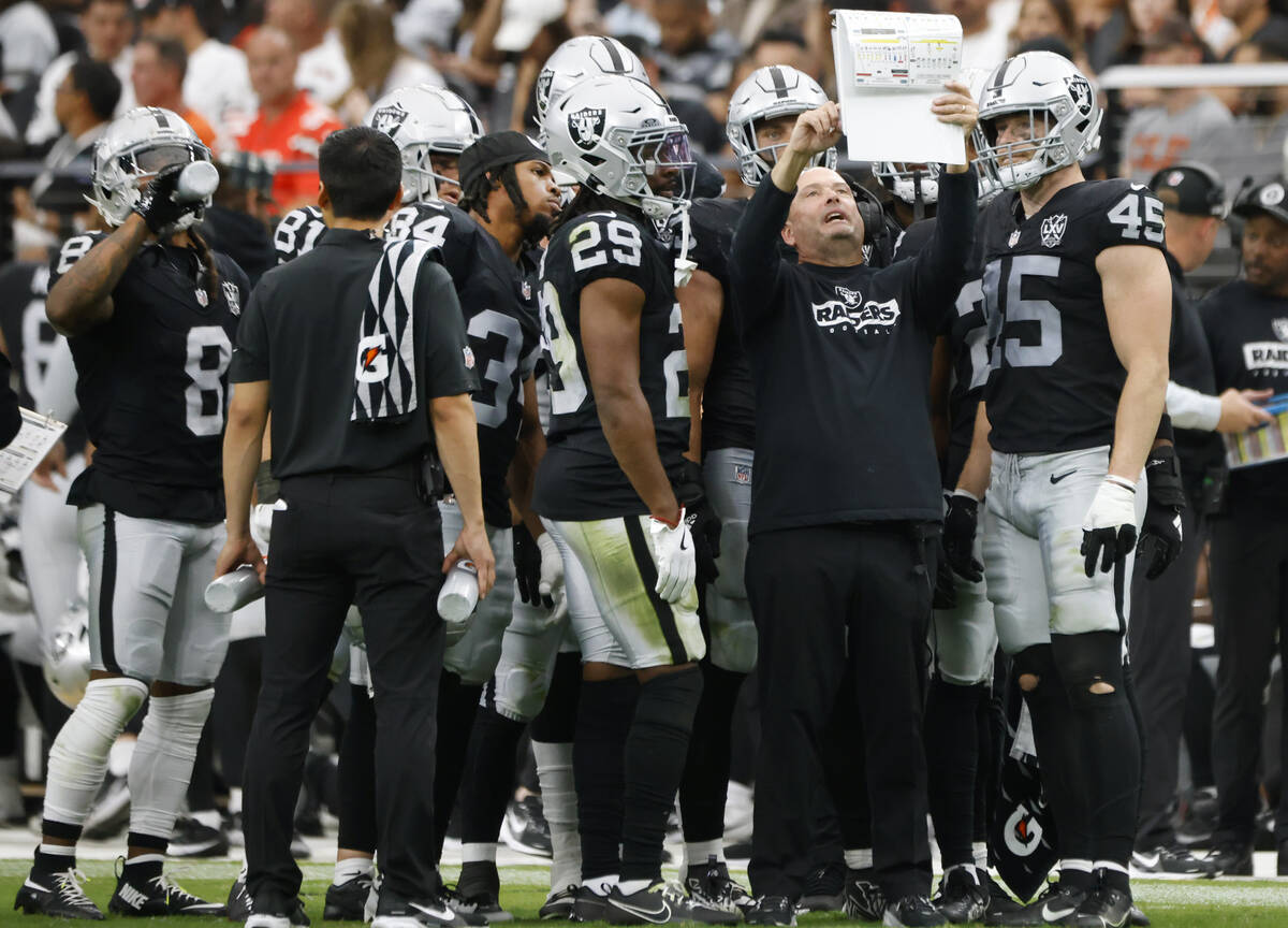 Raiders special teams coordinator Tom McMahon reviews his playbook with players from the sideli ...