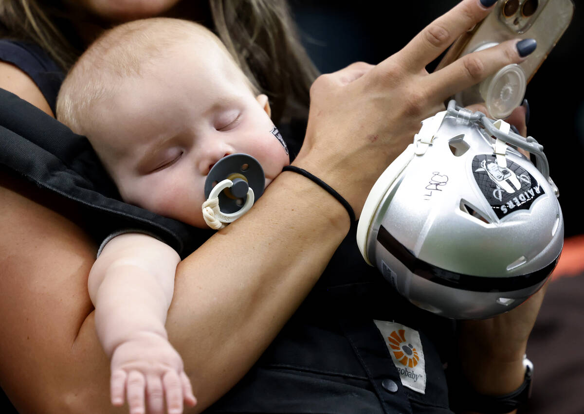 Five-month-old Josiah Brogdon takes a nap on his mother's arm during an NFL game between Raider ...