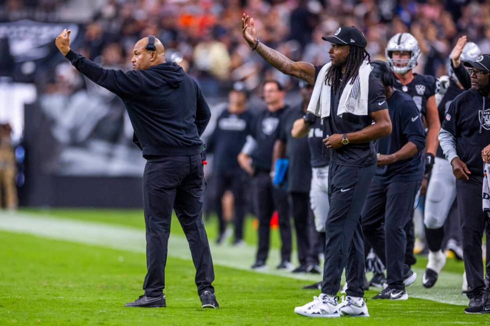 Raiders Head Coach Antonio Pierce and wide receiver Davante Adams (17) signal players on the fi ...