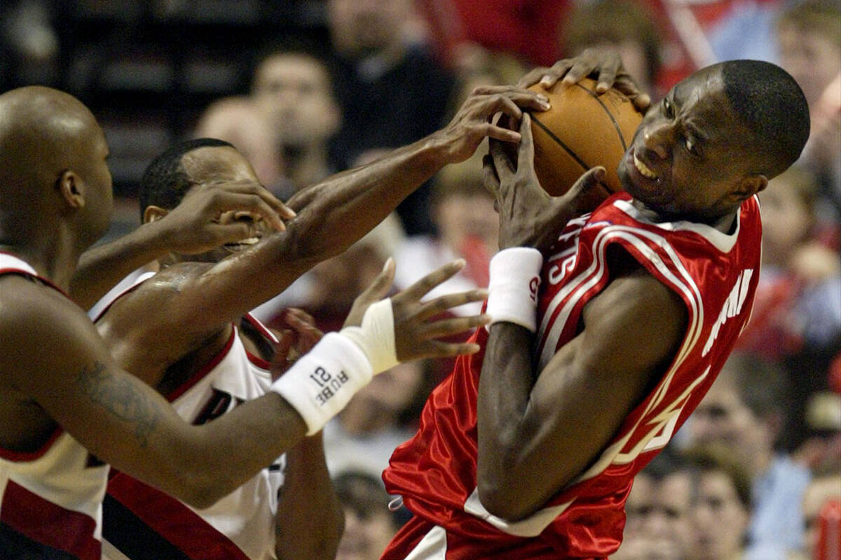 Portland Trail Blazers' Nick Van Exel, left, and Derek Anderson, center, reach in as Houston Ro ...