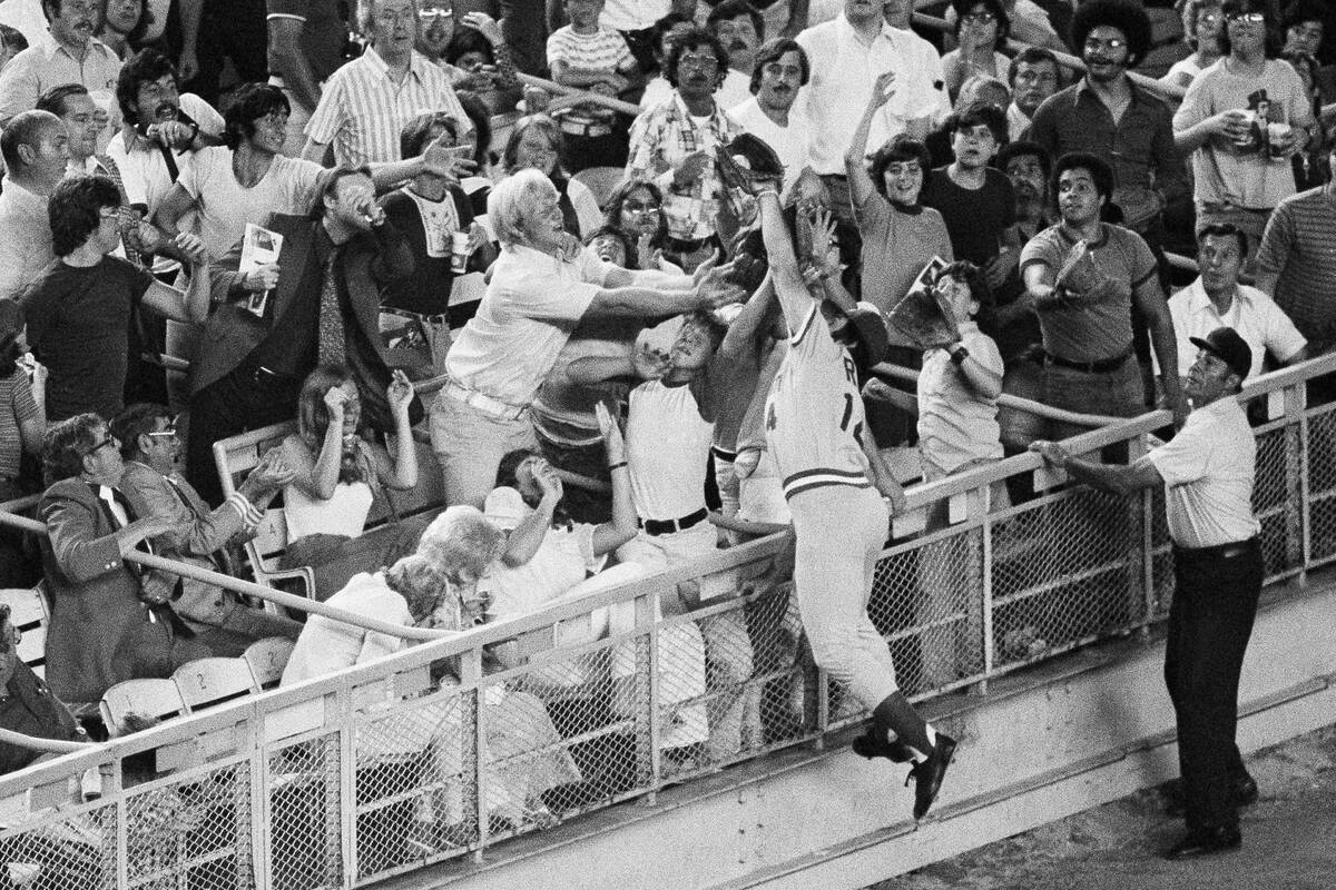 Cincinnati Reds third baseman Pete Rose climbs the rail to catch New York Mets Mike Phillips' p ...