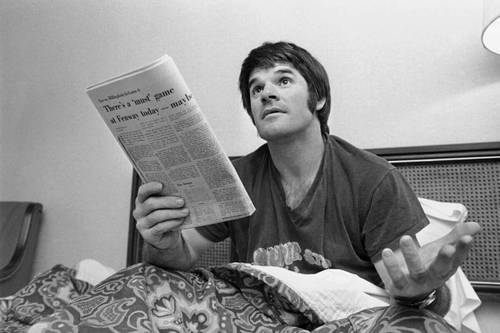 Cincinnati Reds' Pete Rose relaxes on his hotel bed in Boston, Oct. 18, 1975, as he reads paper ...