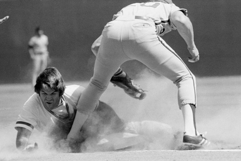 Cincinnati Reds runner Pete Rose knocks the bag loose as he goes headfirst under the tag attemp ...