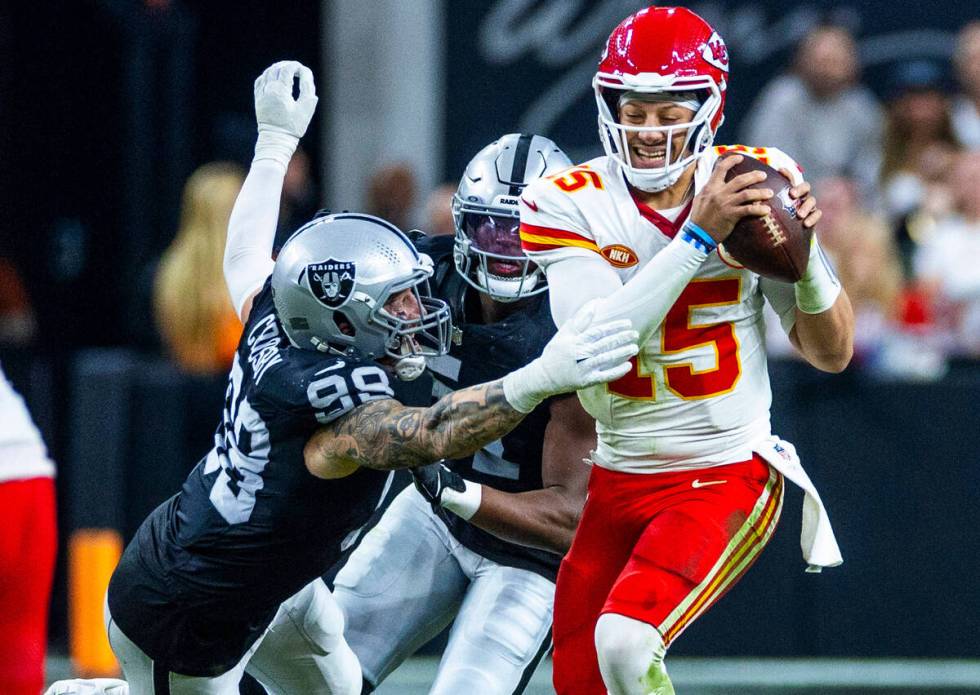 Raiders defensive end Maxx Crosby (98) grabs Kansas City Chiefs quarterback Patrick Mahomes (15 ...