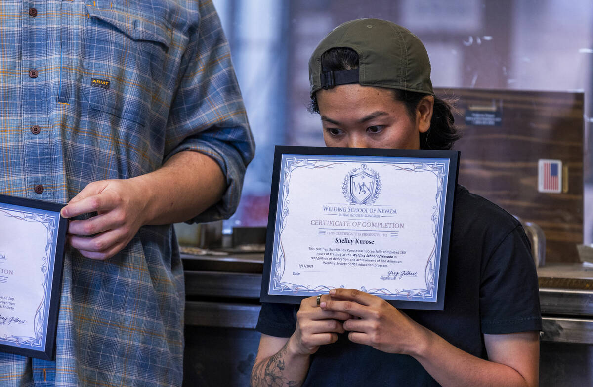 Student Shelley Kurose hides behind her diploma during a graduation event at the Welding School ...