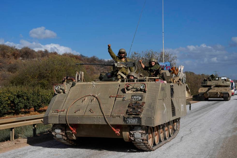 Israeli soldiers raise their fists from a moving APC in northern Israel near the Israel-Lebanon ...