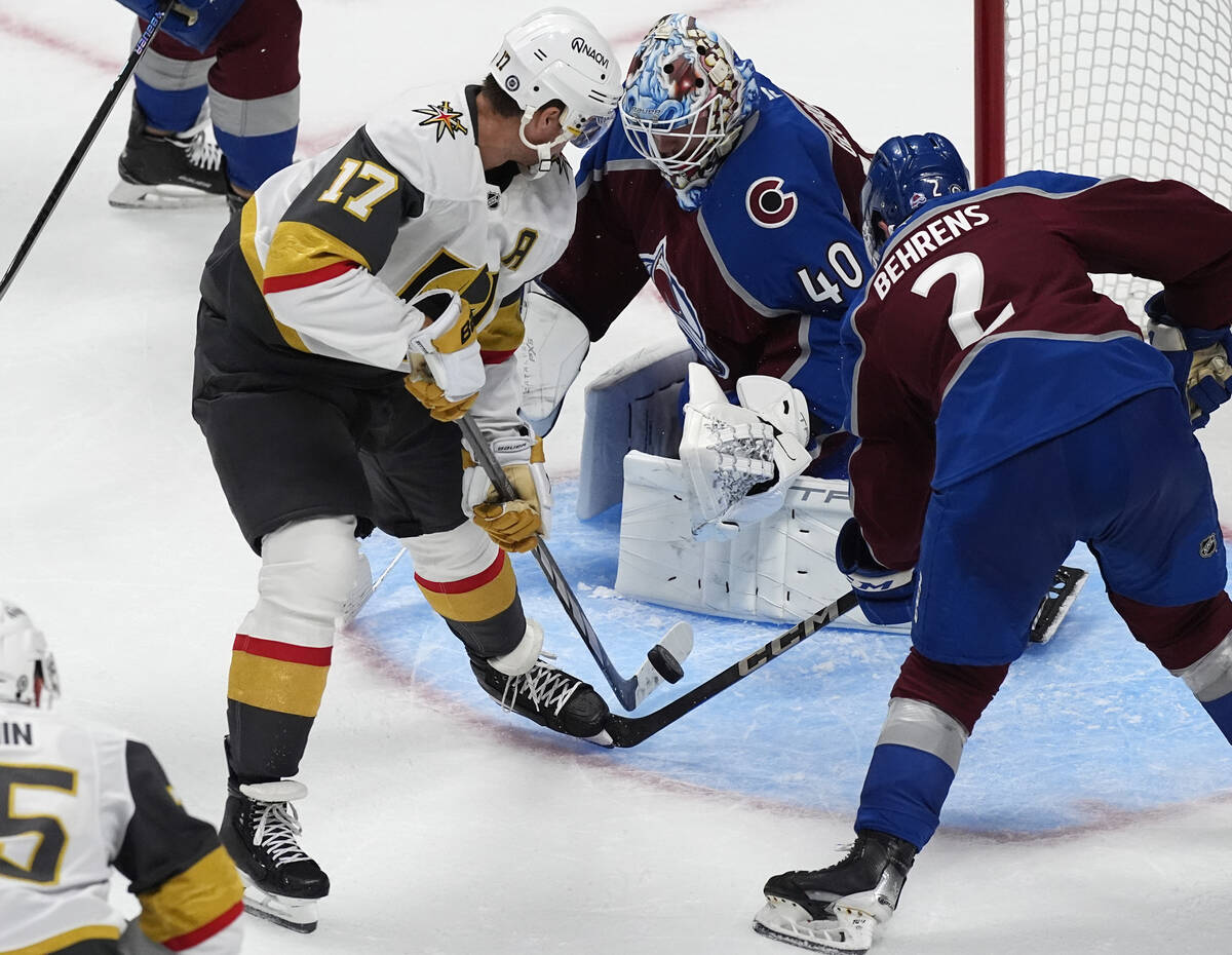 Vegas Golden Knights defenseman Ben Hutton, left, takes a shot as Colorado Avalanche goaltender ...