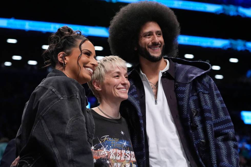 Megan Rapinoe, center, Colin Kaepernick, right, and Nessa Diab, left, pose for photographs duri ...