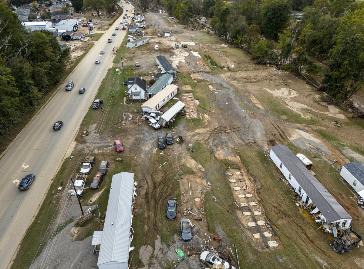 Homes and vehicles that were damaged in a flash flood from Hurricane Helene lie on the side of ...