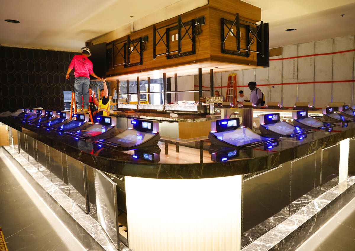 Workers install a large screen TV at the expanded Center Bar at the CasaBlanca hotel-casino, on ...