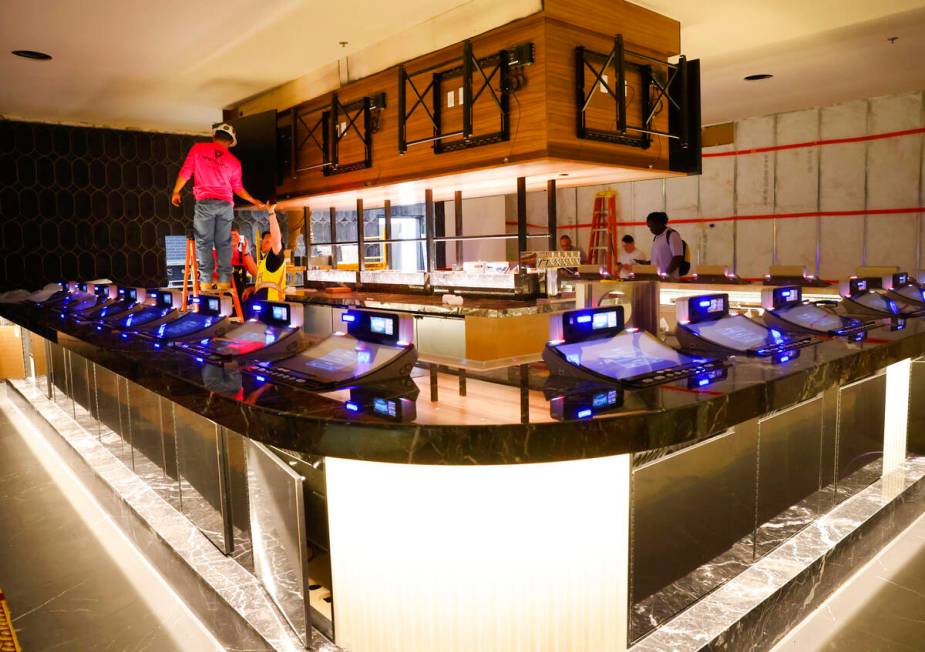 Workers install a large screen TV at the expanded Center Bar at the CasaBlanca hotel-casino, on ...