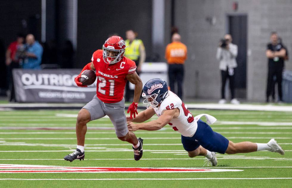 UNLV wide receiver Jacob De Jesus (21) avoids Fresno State defensive lineman Isiah Chala Jr. (5 ...