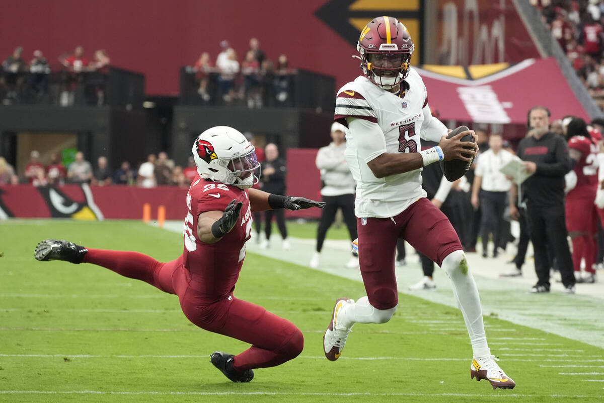 Washington Commanders quarterback Jayden Daniels, right, runs past Arizona Cardinals linebacker ...