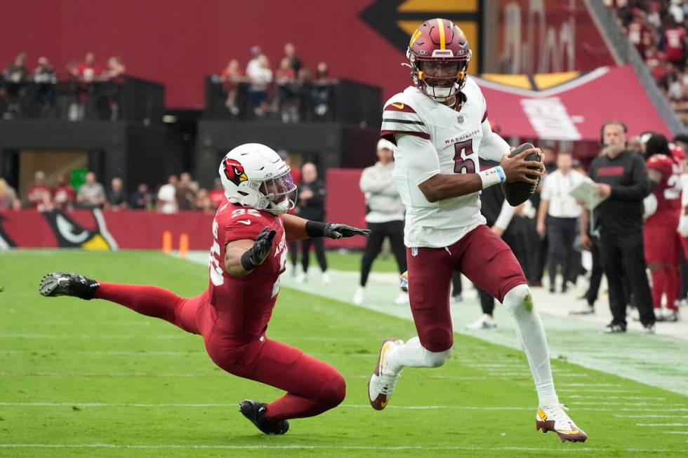 Washington Commanders quarterback Jayden Daniels, right, runs past Arizona Cardinals linebacker ...