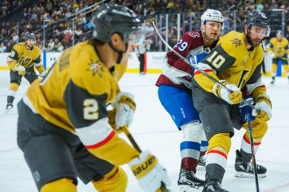 Golden Knights center Nicolas Roy (10) watches the puck as his teammate Golden Knights defensem ...