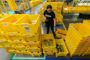 FILE - An employee scans incoming items at a receiving station at the Amazon OXR1 fulfillment c ...