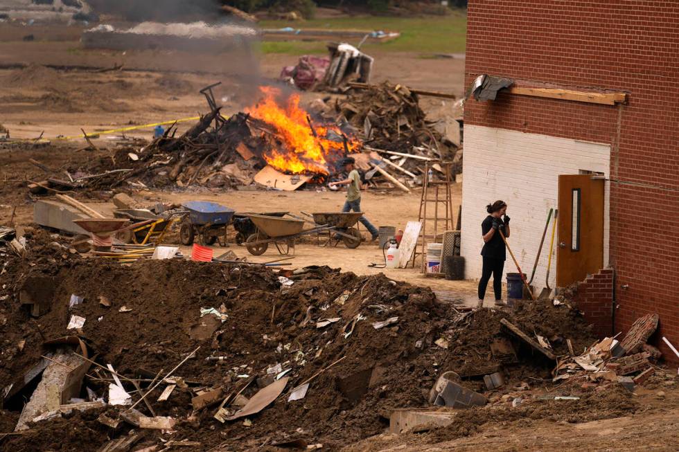 People clean up and burn debris left in the aftermath of Hurricane Helene Friday, Oct. 4, 2024, ...