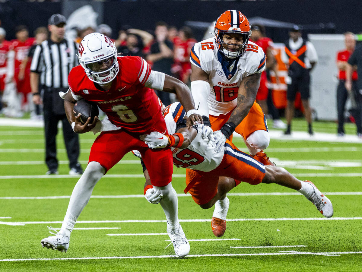 UNLV quarterback Hajj-Malik Williams (6) looks to shake off a tackle on a run against Syracuse ...