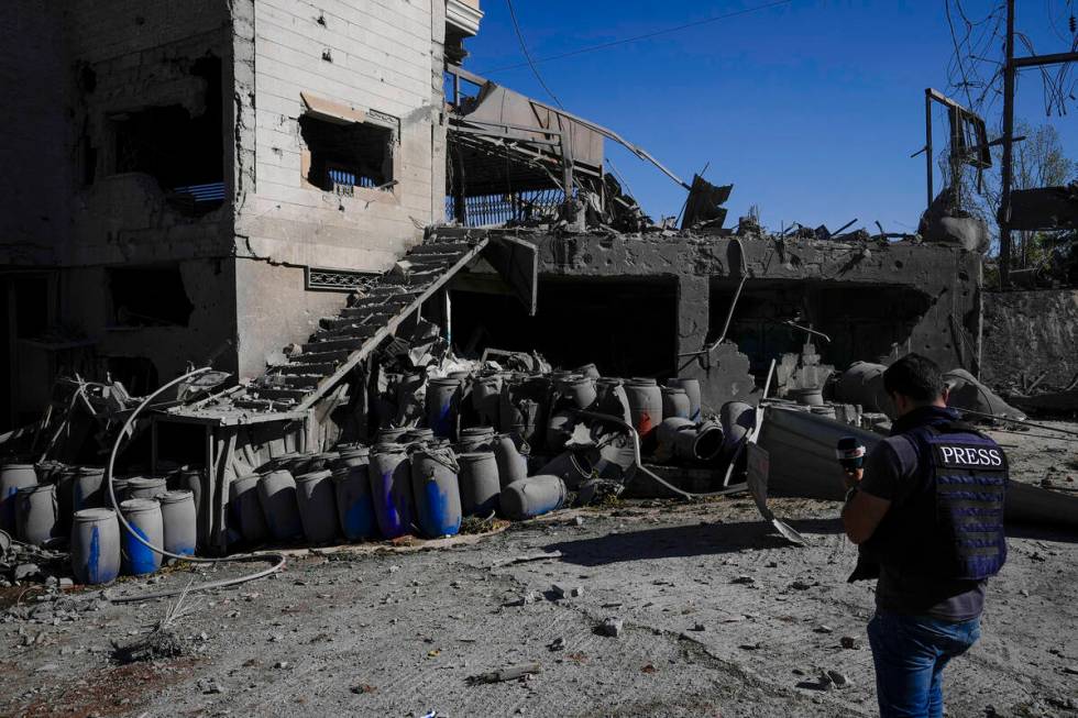 A journalist documents the damaged buildings at the site of an Israeli airstrike, in the villag ...