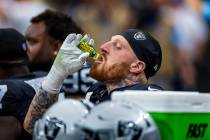 Raiders defensive end Maxx Crosby (98) drinks a bottle of Pickle Juice on the bench against the ...