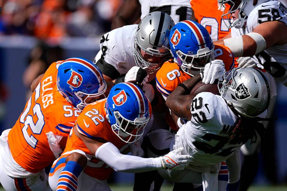 Las Vegas Raiders running back Alexander Mattison (22) is tackled by Denver Broncos safety P.J. ...