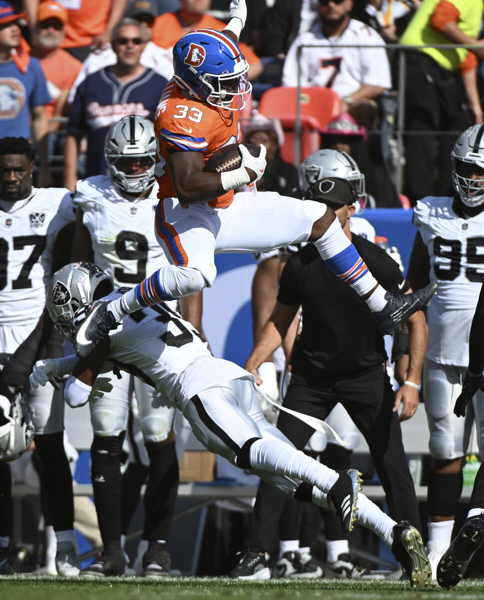 Denver Broncos running back Javonte Williams (33) leaps over Las Vegas Raiders cornerback Nate ...