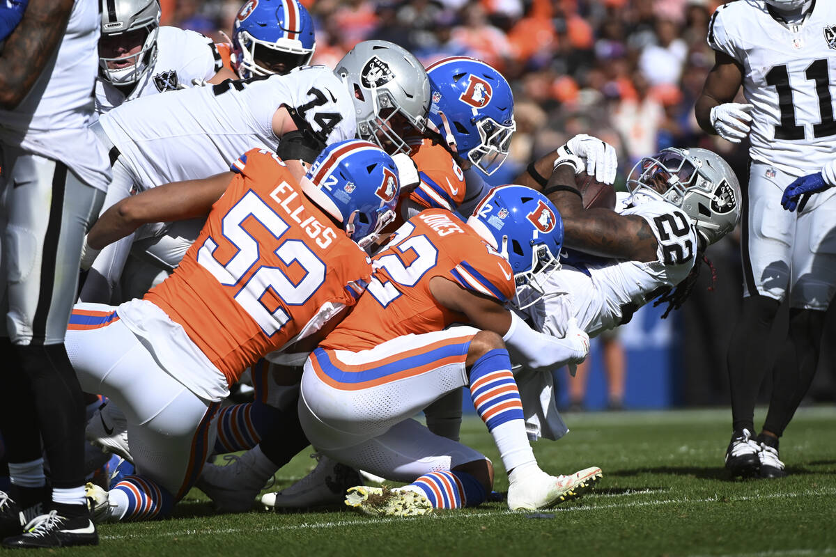 Las Vegas Raiders running back Alexander Mattison (22) is tackled by Denver Broncos safety Bran ...