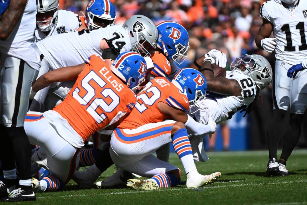 Las Vegas Raiders running back Alexander Mattison (22) is tackled by Denver Broncos safety Bran ...