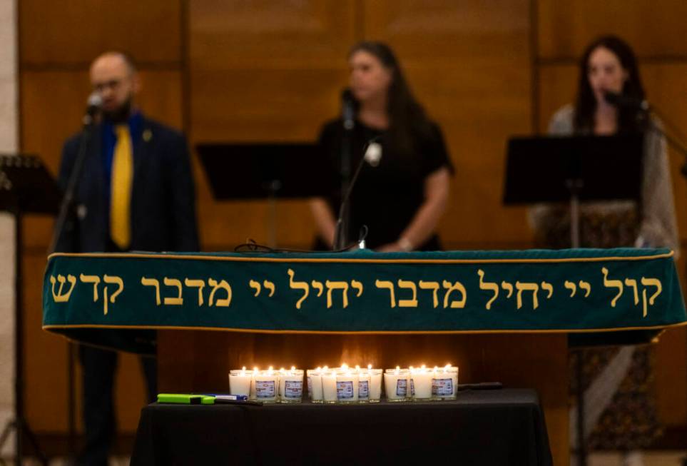 Singers perform as candles burn during a ceremony at Midbar Kodesh Temple marking one year sinc ...