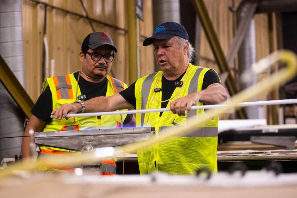 Todd Fisher, right, heats up a neon tube before bending it with guidance from YESCO neon bender ...