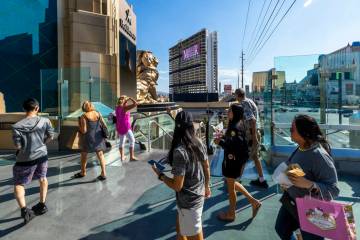 People walk about the MGM Grand pedestrian bridge while stealing a look at the Tropicana with i ...