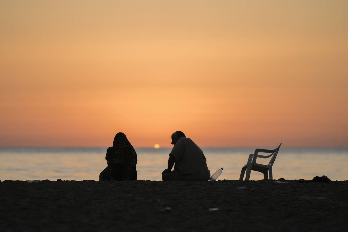 A displaced couple sits at Ramlet al-Baida public beach after fleeing the Israeli airstrikes in ...