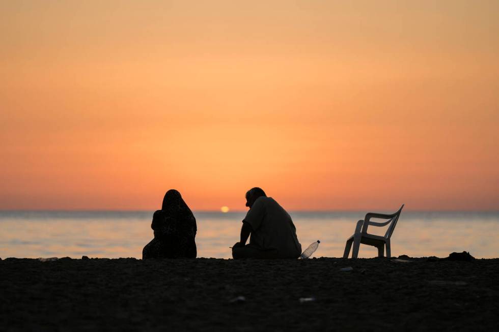 A displaced couple sits at Ramlet al-Baida public beach after fleeing the Israeli airstrikes in ...